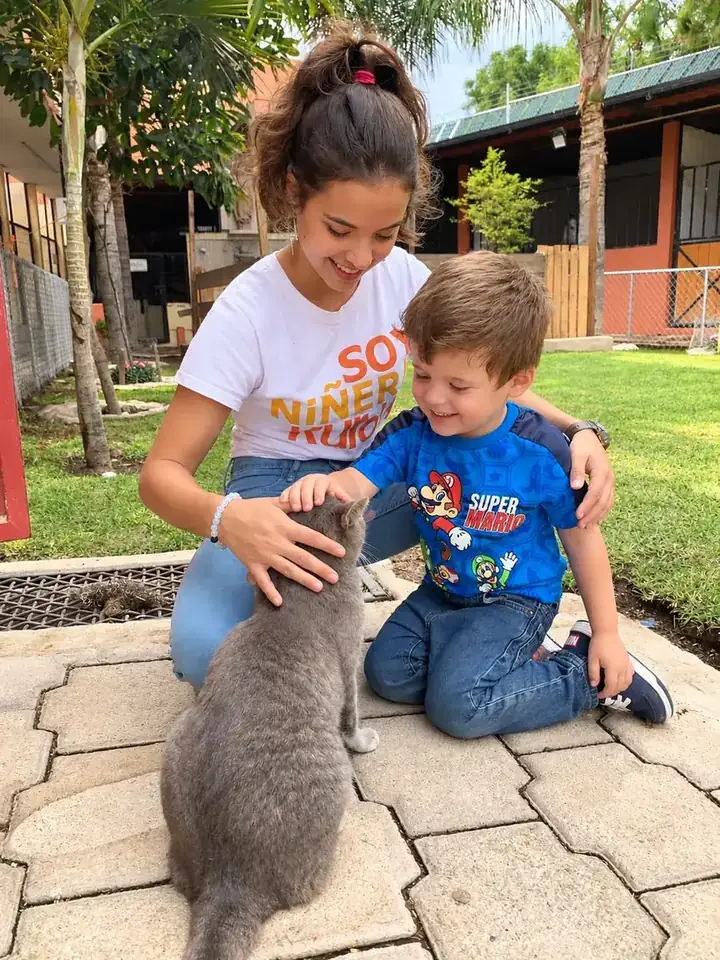Niñera Kurowi y un niño acariciando a un gato en el jardín